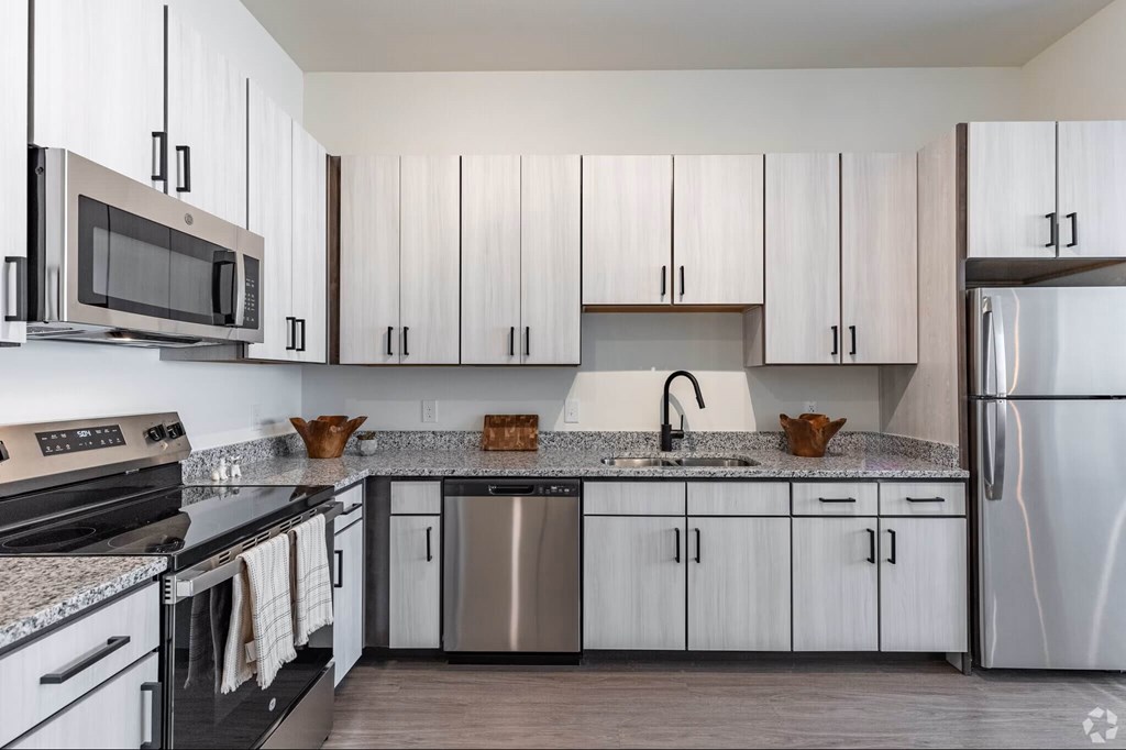 A modern kitchen with white cabinets and stainless steel appliances.