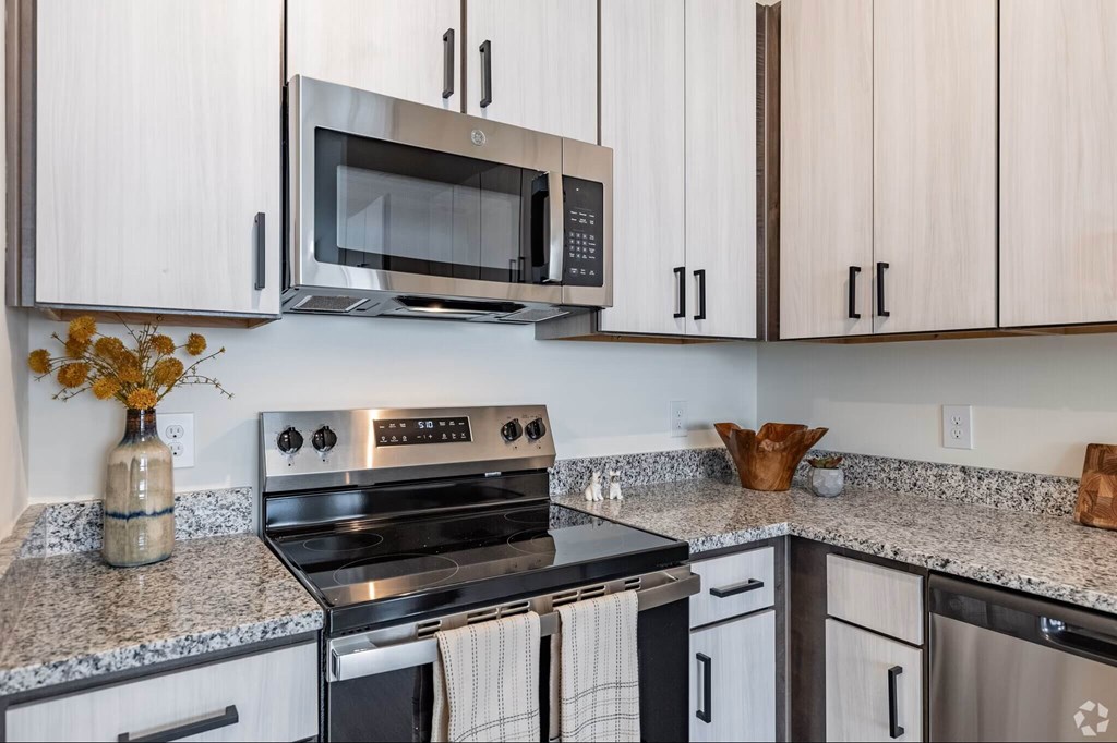 A modern kitchen with a stove, microwave, and cabinets.