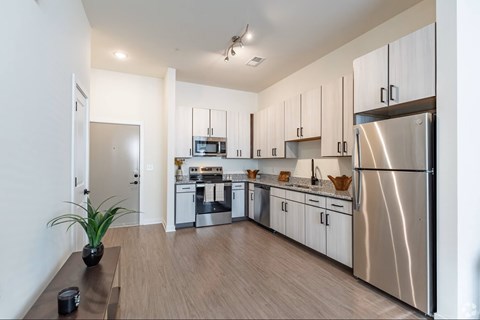 A modern kitchen with a stainless steel refrigerator and wooden flooring.