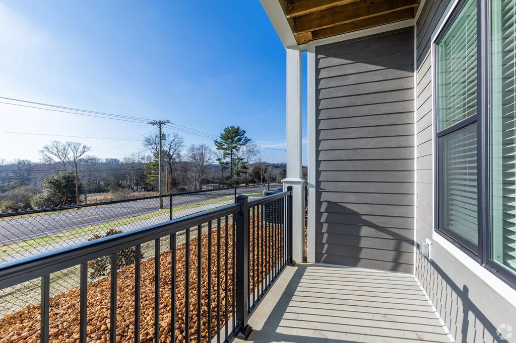A balcony with a metal railing and a view of a hill with trees.