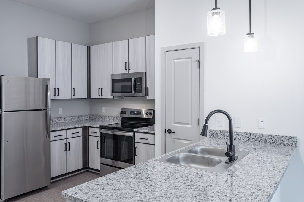 A kitchen with a granite countertop and stainless steel appliances.