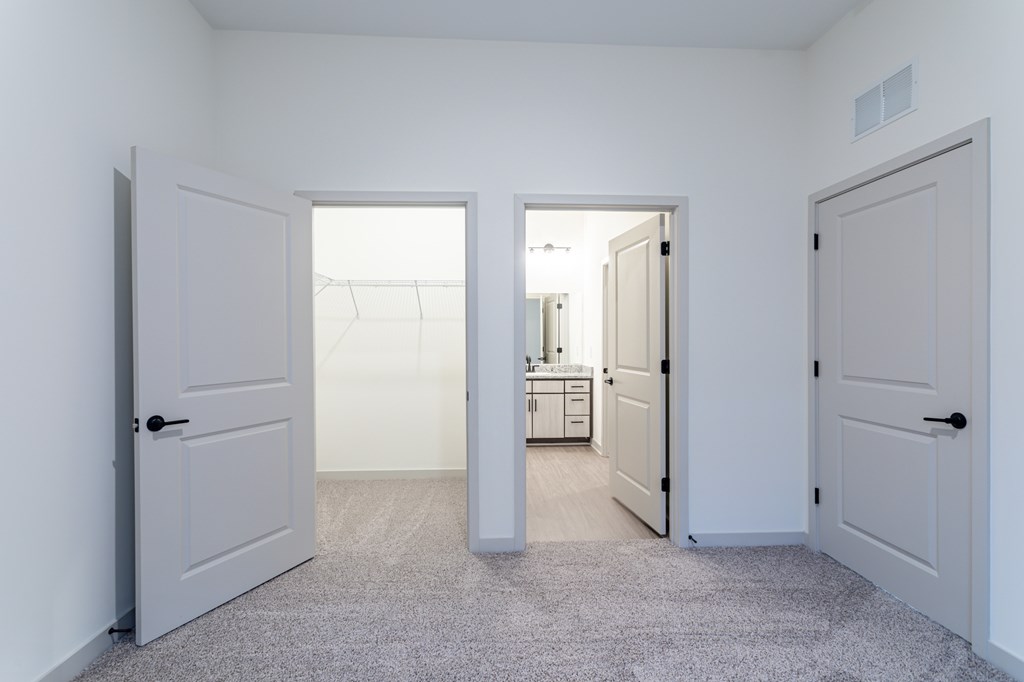 A white hallway with a carpeted floor and two open doors.