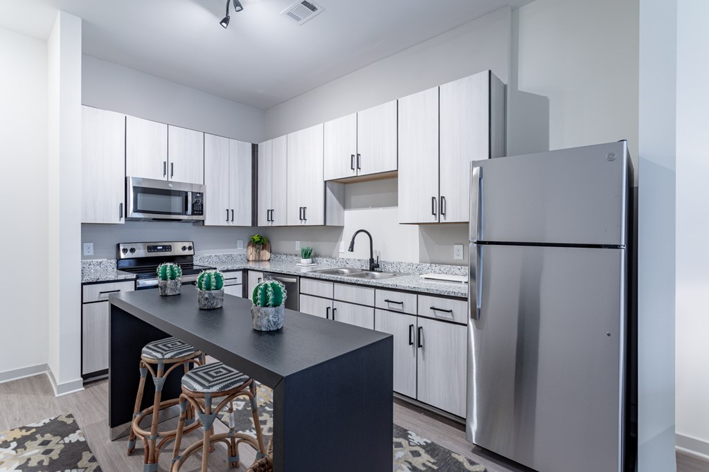 A modern kitchen with a black countertop and stools.