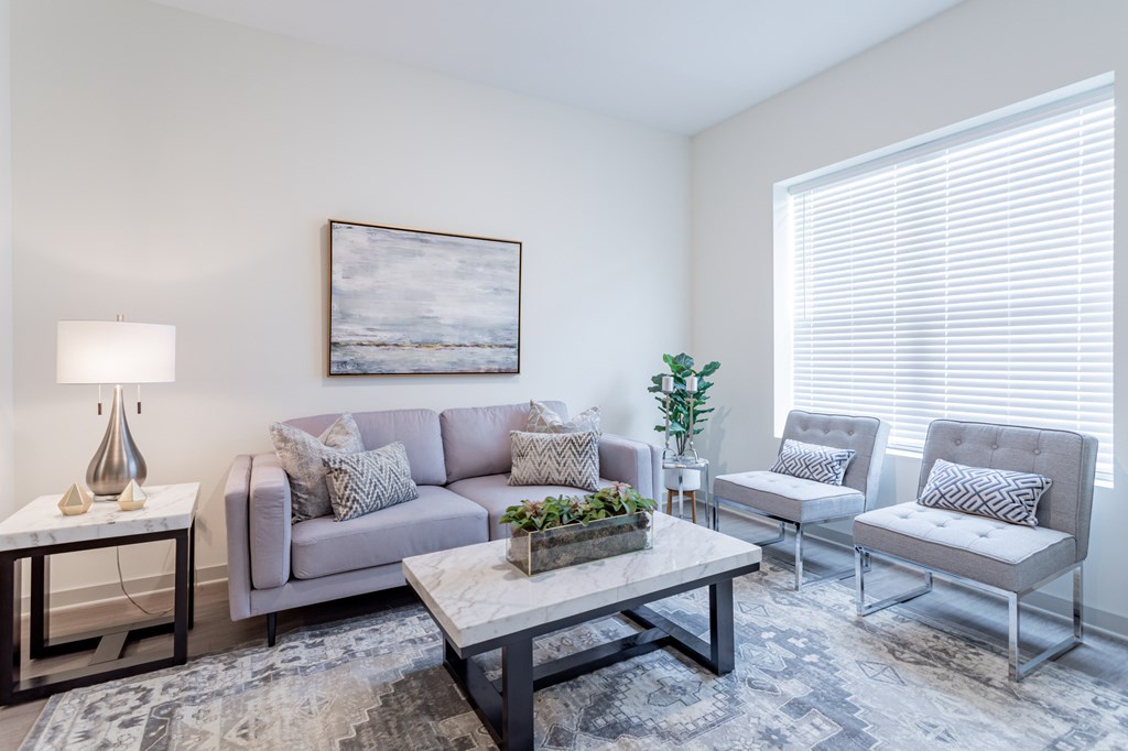 A living room with a grey couch, a coffee table, and a painting on the wall.