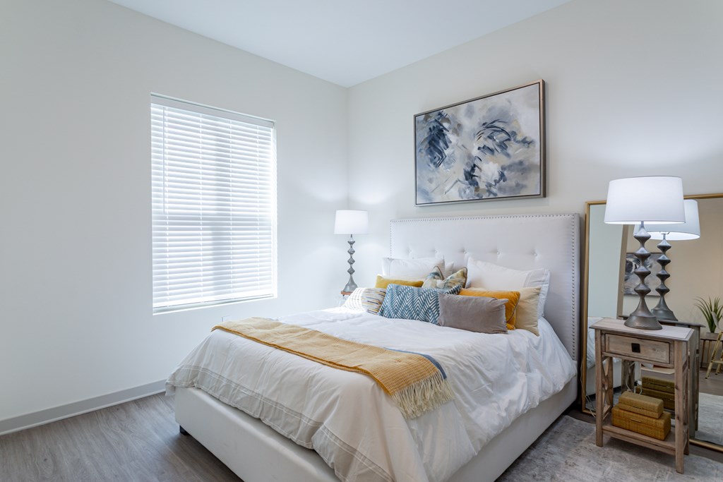 A bedroom with a white bed and a painting above it.
