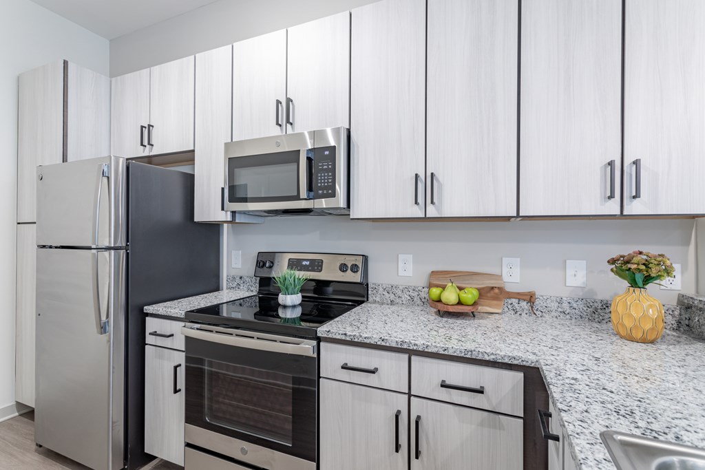 A kitchen with a stainless steel refrigerator, oven, and microwave.