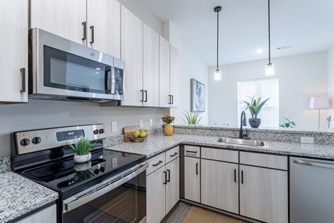 A modern kitchen with a black stove and white cabinets.
