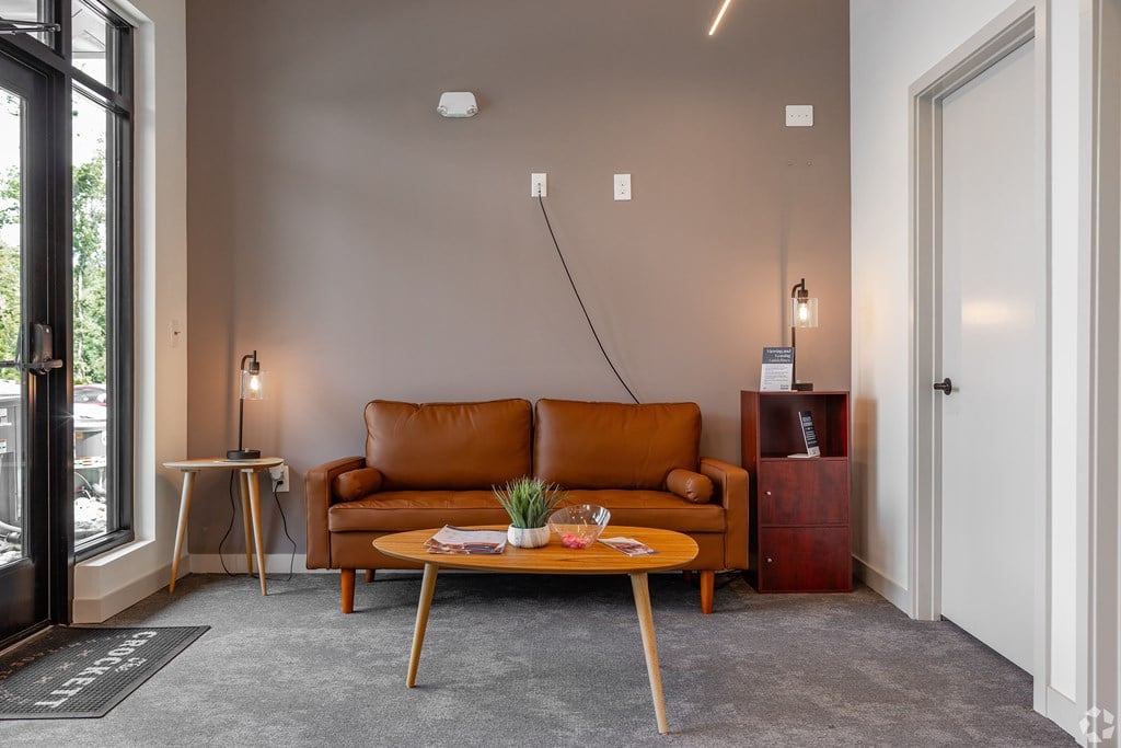 A living room with a brown leather couch and a wooden coffee table.