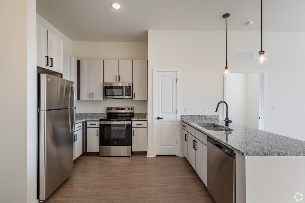A modern kitchen with stainless steel appliances and wooden flooring.