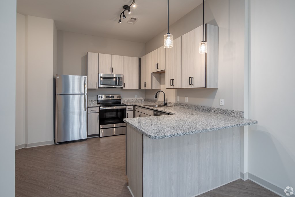 A kitchen with a stainless steel refrigerator, microwave, oven, and sink.