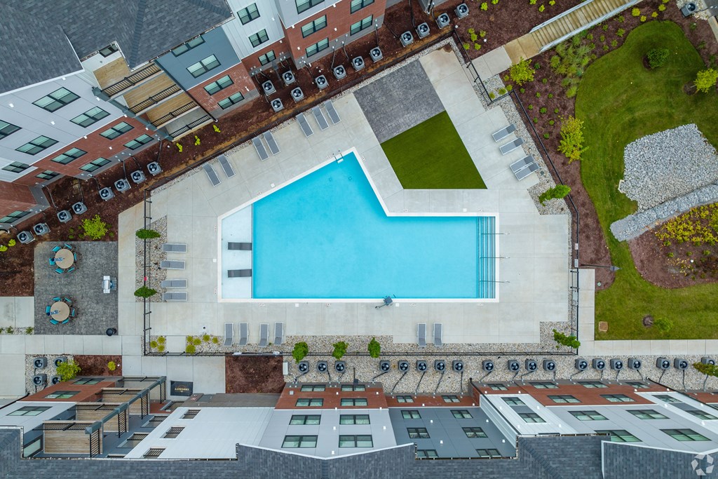 A swimming pool is surrounded by a patio and apartment buildings.