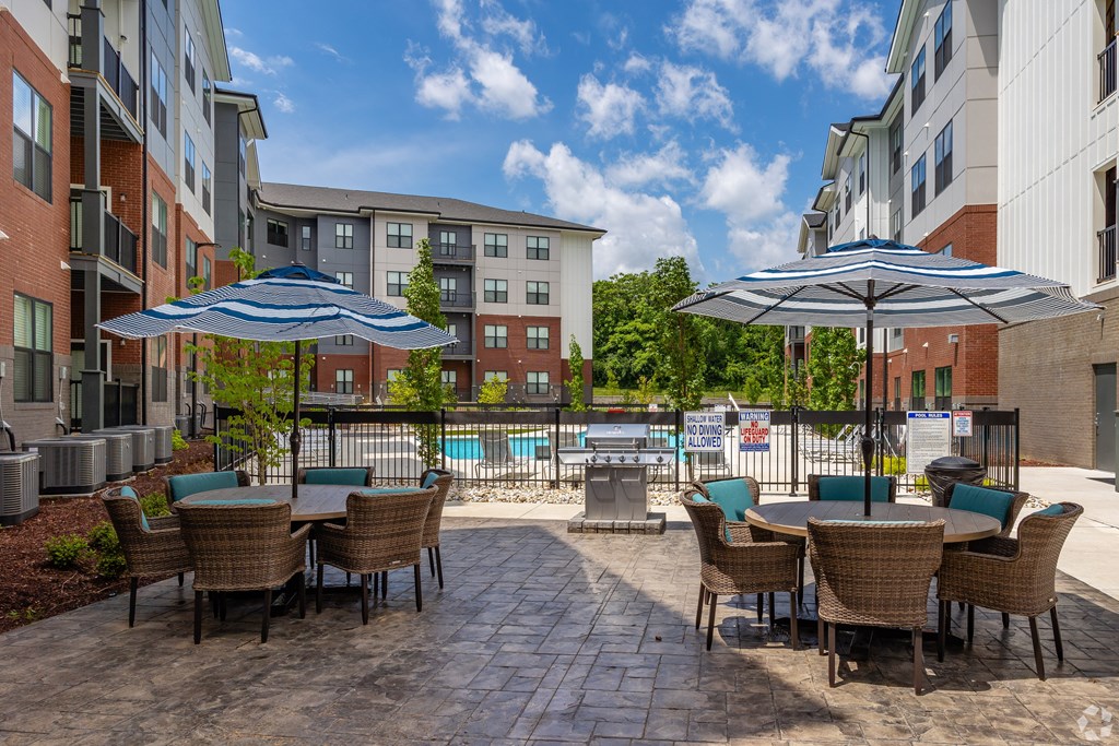 A patio with chairs and umbrellas overlooking a pool.