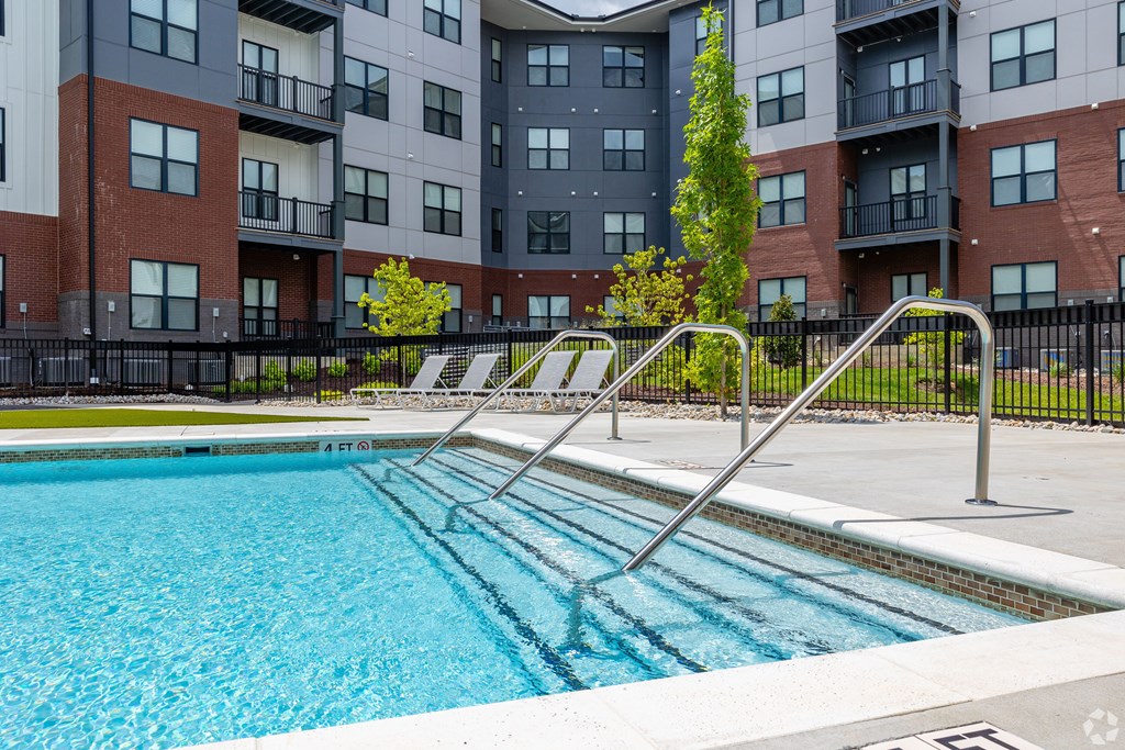 A swimming pool in front of a multi-story apartment building.