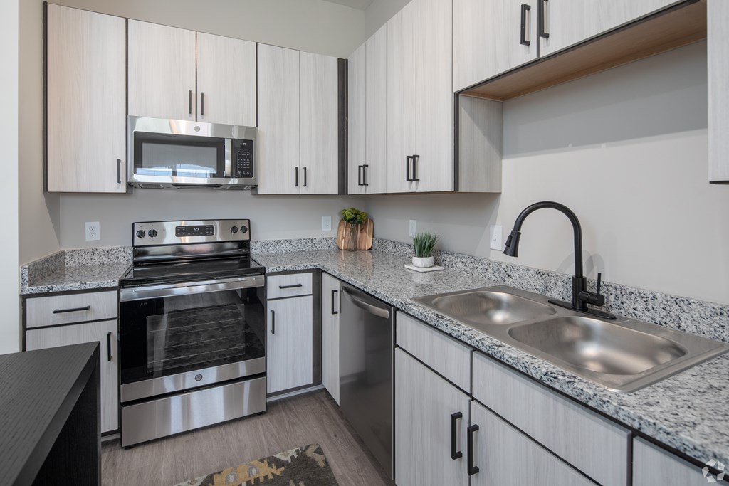 A modern kitchen with granite countertops and stainless steel appliances.