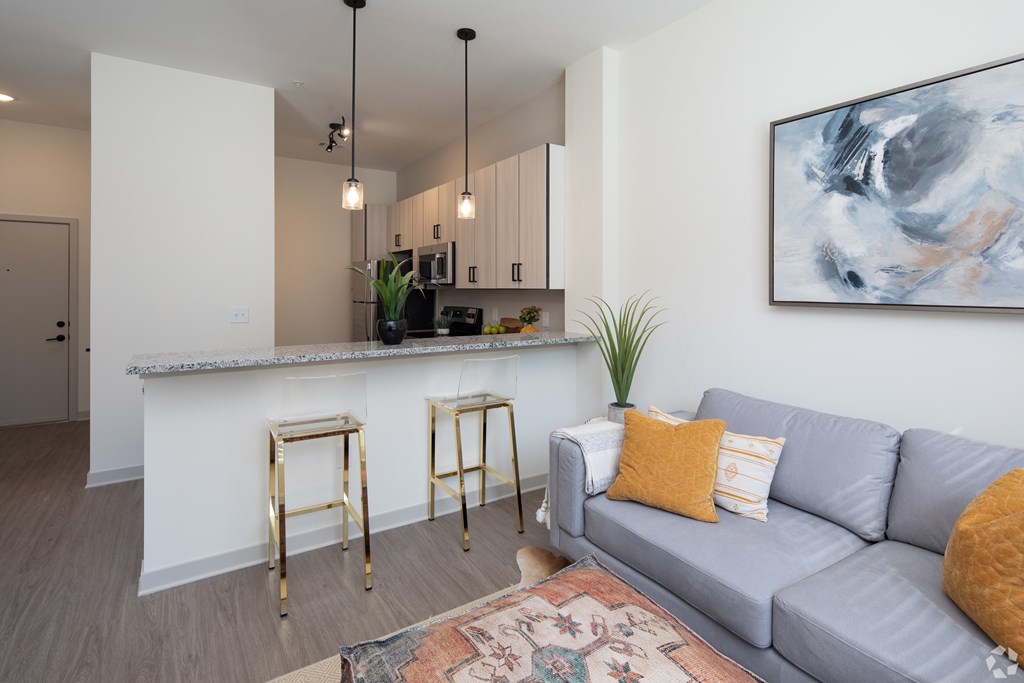 A living room with a grey couch and a bar area.