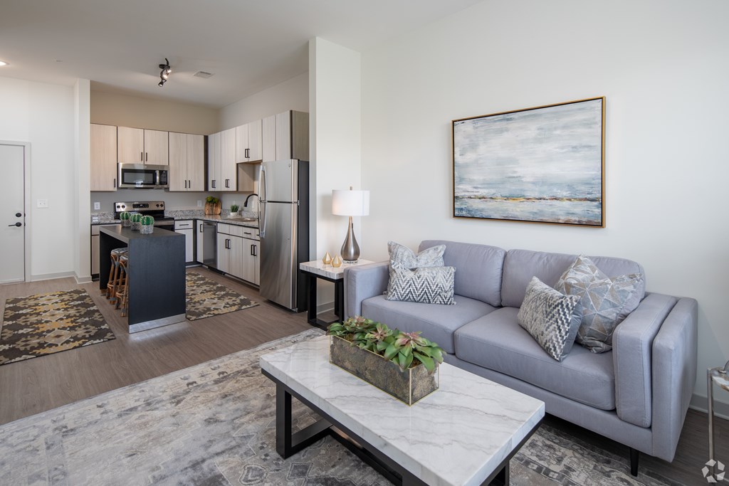 A modern living room with a grey couch and a painting on the wall.