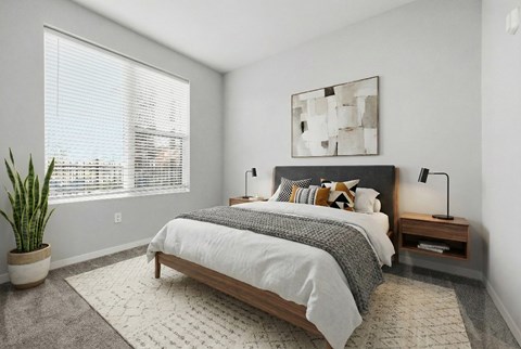 A bedroom with a large bed, a potted plant, and a painting on the wall.