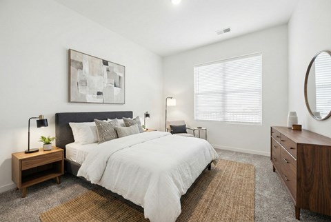 A bedroom with a large bed, a nightstand with a lamp, and a painting on the wall.