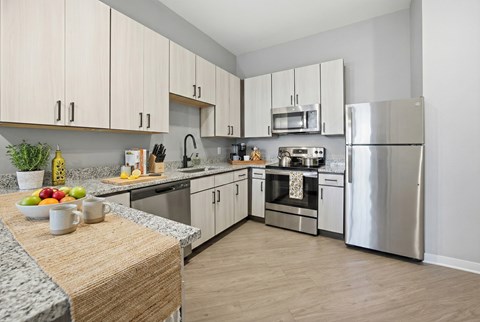 A kitchen with a refrigerator, oven, and sink.