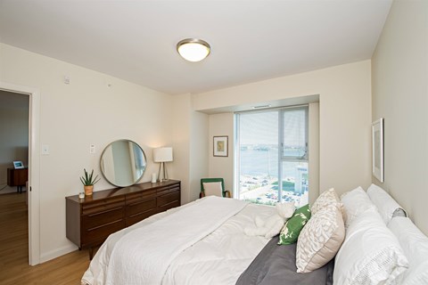 A bedroom with a large bed and a mirror on the dresser.