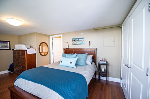 A bedroom with a bed, nightstand, and dresser.