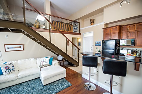 A living room with a staircase and a kitchen area.