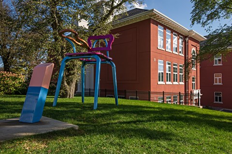 A playground with a blue and pink slide in front of a red building.