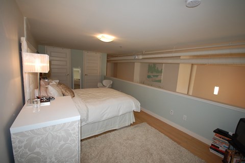 A bedroom with a bed, nightstand, and lamp.