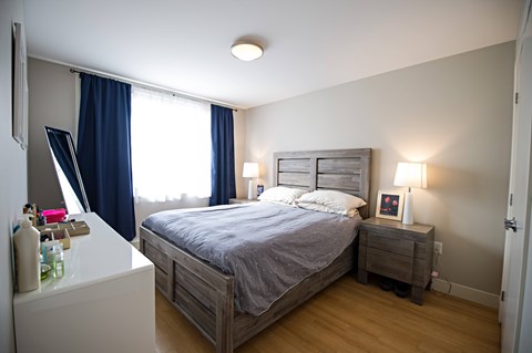 A bedroom with a bed, nightstand, and window with blue curtains.