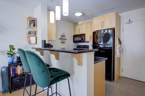 A kitchen with a green chair and a black countertop.