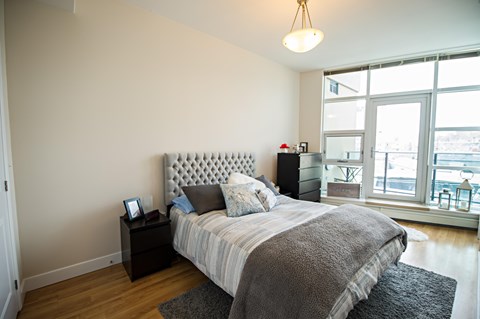 A bedroom with a large bed and a window overlooking a cityscape.