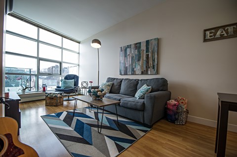 A living room with a grey couch and a guitar on the floor.