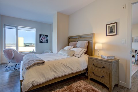 A bedroom with a large bed and a chair by the window.