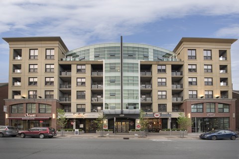 A large building with a glass center and a red car in front of it.
