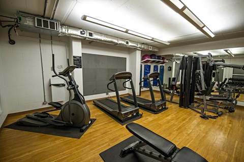 A gym with a variety of equipment including treadmills, weights, and exercise machines.