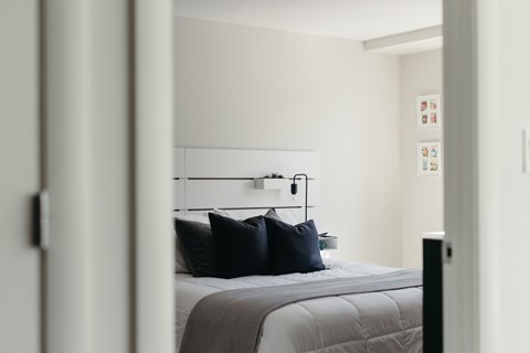 A bedroom with a bed and a wall-mounted shelf with pictures.