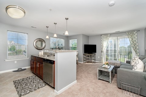 A well-lit, spacious kitchen and living room with a television and a couch.