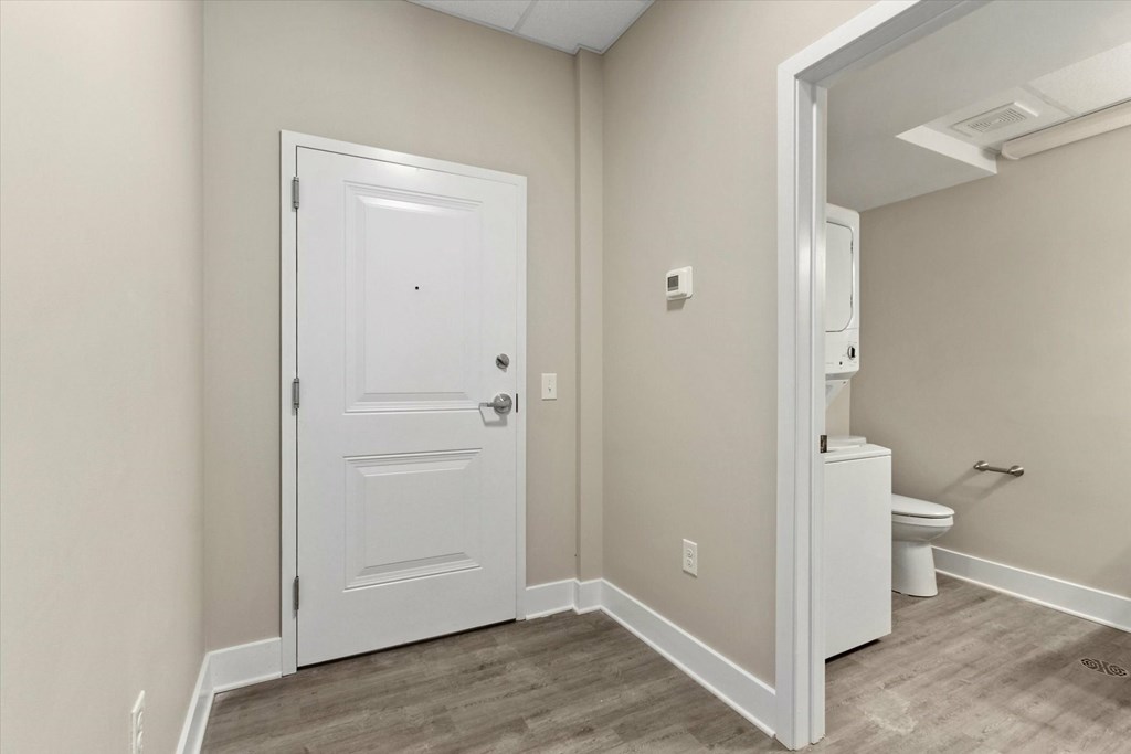 A white door is in a room with a toilet in the corner.