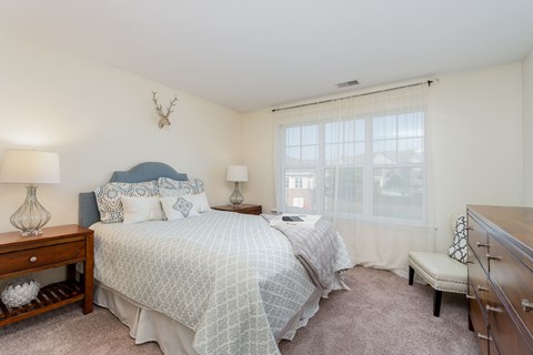 A bedroom with a bed, nightstands, and a window.