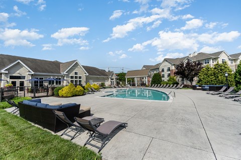 A swimming pool surrounded by lounge chairs and apartment buildings.