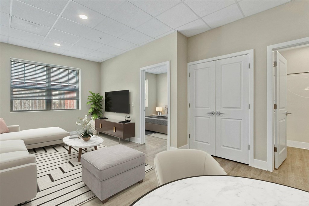 A living room with a white couch, a coffee table, and a television.