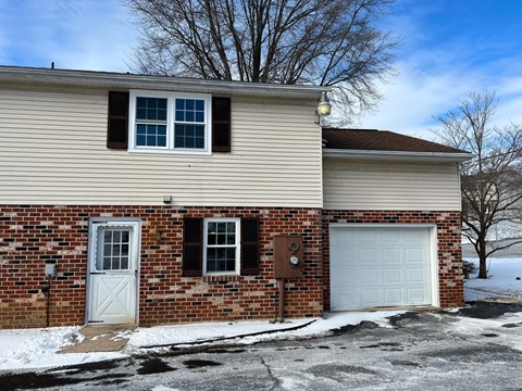 A house with a white garage door and a brown door.