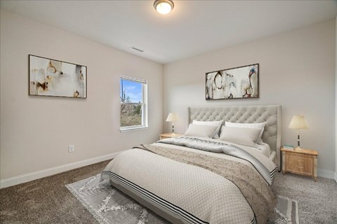 A bedroom with a large bed and two lamps.