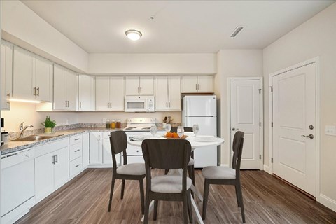 A kitchen with white cabinets and a table with chairs.