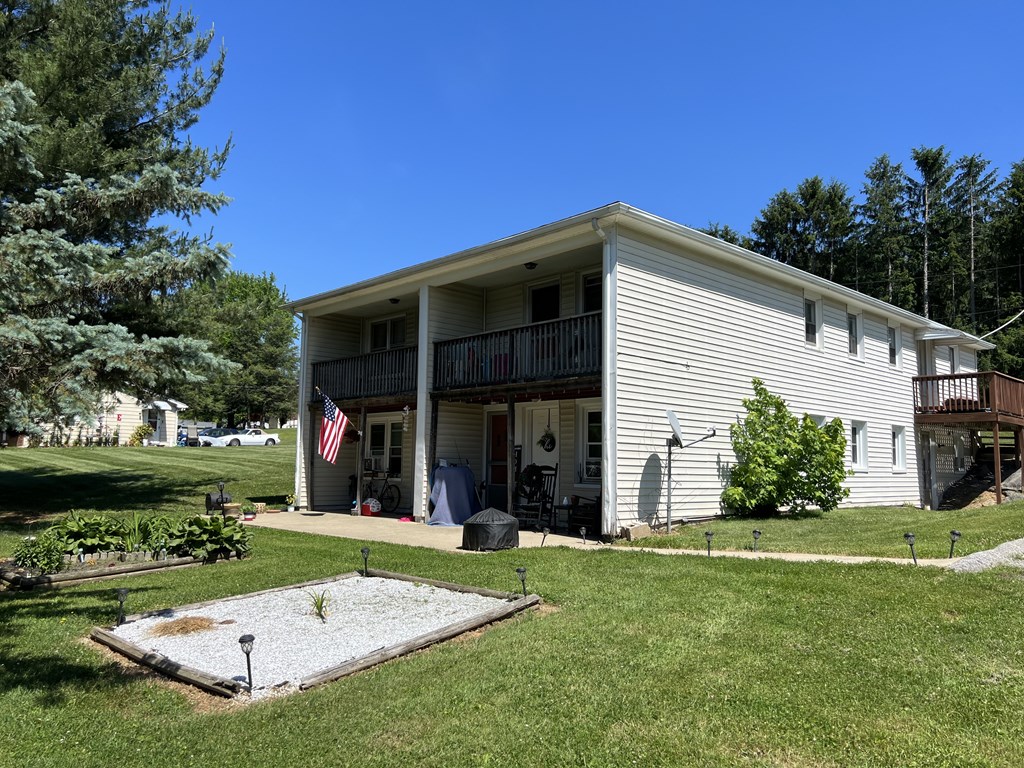 A house with a flag on the porch and a small garden in front.