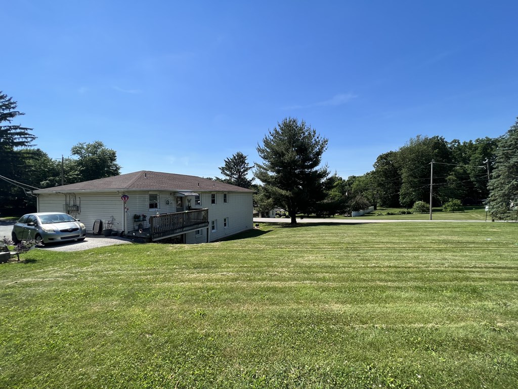 A white house with a brown roof is surrounded by a grassy field.