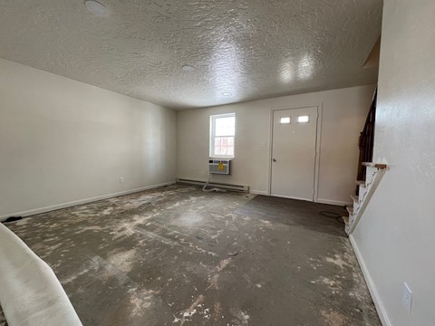 A room with a concrete floor and white walls is shown.