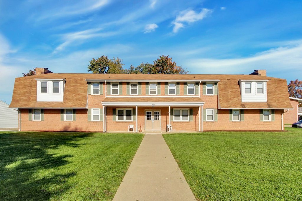A large brick building with a green lawn in front.