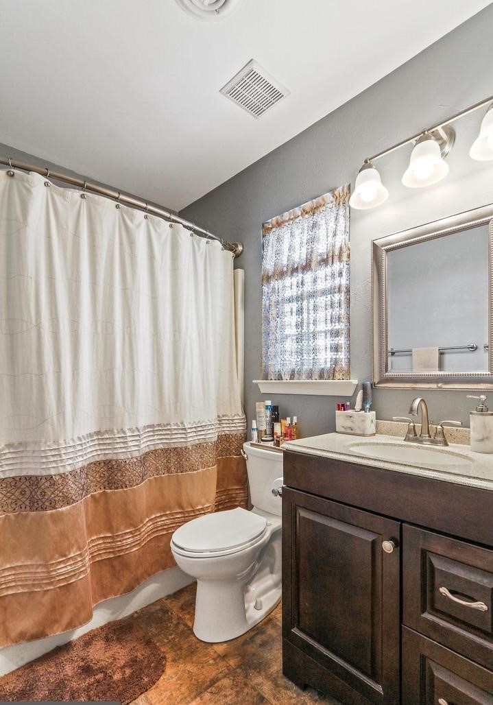 A bathroom with a toilet, sink, and shower curtain.