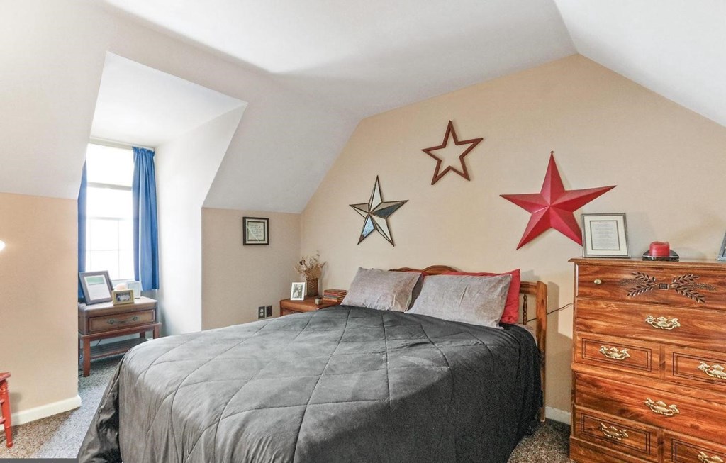 A bedroom with a bed, dresser, and three star decorations on the wall.